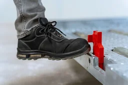 Operator activating manual safety stop on ULD support pallet with foot